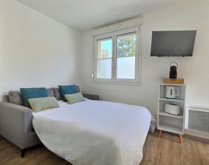een slaapkamer met een groot wit bed en een bank bij Tout Inclus - Plein Centre - Netflix - Moontown in Lunéville