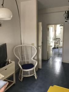 une chaise blanche assise dans une pièce avec télévision dans l'établissement Appartamento panoramico centro, à Riccione