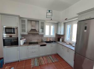 una cocina con armarios blancos y electrodomésticos de acero inoxidable en Lighthouse View Syros, en Azolimnos