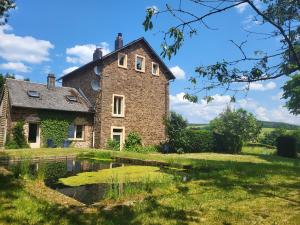 uma antiga casa de pedra com um lago no quintal em Die alte Schule Häuschen em Sankt Vith