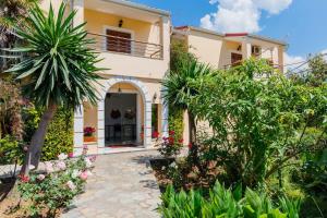 una casa con una palmera delante de ella en ILENA HOTEL en Acharavi