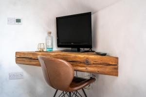 a desk with a television on a wall with a chair at Plockton Shoreside House in Plockton