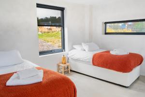 two beds in a white room with two windows at Plockton Shoreside House in Plockton