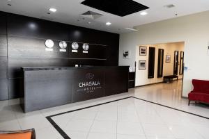 a lobby with a reception desk and a red chair at Chagala Aktau Hotel in Aktau