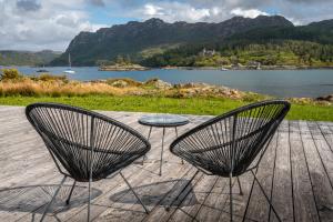 two chairs and a table with a view of a lake at Plockton Shoreside House in Plockton