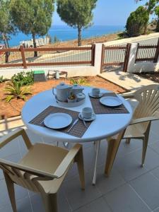 una mesa azul con 2 sillas y una mesa con platos y tazas en Seaclusion Vacation Villa, en Pomos