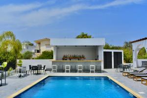 a swimming pool with tables and chairs next to a house at Zoi Ayia Napa in Ayia Napa