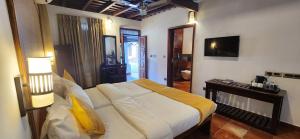 a bedroom with a bed and a desk and a television at Kumarakom Tharavadu - A Heritage Hotel, Kumarakom in Kumarakom