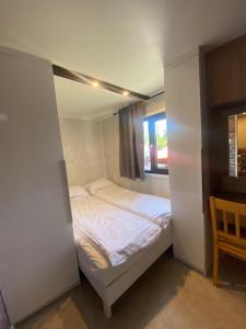 małe łóżko w małym pokoju z oknem w obiekcie Domy nad morzem - Chata Pirata- Tiny House w Dziwnowie