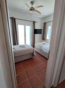 een slaapkamer met 2 bedden en een plafondventilator bij Lighthouse View Syros in Azolimnos
