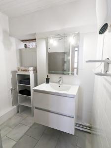 La salle de bains blanche est pourvue d'un lavabo et d'un miroir. dans l'établissement Le Saint Jean Cosy et Confort, à Villefranche-de-Conflent