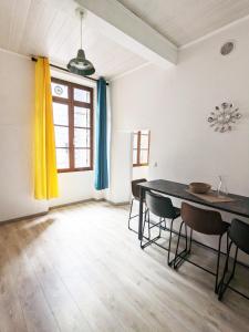 una sala da pranzo con tavolo, sedie e una finestra di Le Saint Jean Cosy et Confort a Villefranche-de-Conflent