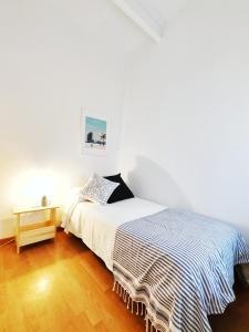 a white bedroom with a bed and a table at Acogedor Apartamento en Barcelona Forum Sant Adrià in Sant Adria de Besos