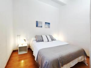 a white bedroom with a bed and a night stand at Acogedor Apartamento en Barcelona Forum Sant Adrià in Sant Adria de Besos
