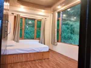 a small bedroom with a bed and a window at Cabin in the Woods in Vashisht