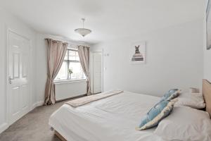 a white bedroom with a bed and a window at Beach Front House in Walton-on-the-Naze