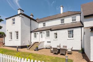 una casa blanca con una mesa y bancos frente a ella en South Wing of Edwinstowe Hall, en Edwinstowe