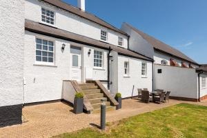 a white house with a patio and a table at South Wing of Edwinstowe Hall in Edwinstowe