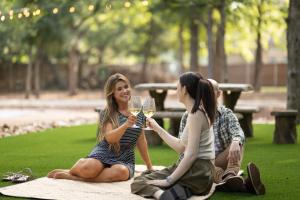 two women sitting on a picnic blanket with glasses of wine at 7744 Ranch Glamping Resort in Austin