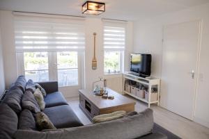 a living room with a couch and a tv at Vakantiewoning op het sluisplateau 23 Wemeldinge in Wemeldinge