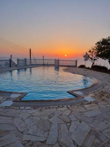 una piscina con puesta de sol en el fondo en Seaclusion Vacation Villa, en Pomos