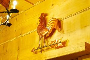 a wooden rooster sign on a wall with a arrow at Browar POD CZARNYM KOGUTEM in Cieszyn