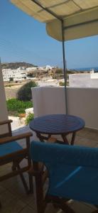 a blue table and chairs on a balcony with an umbrella at Elzahed apartments bonaccia in Kimolos