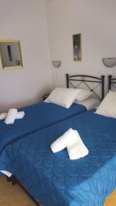 two beds in a bedroom with blue sheets and white towels at Elzahed apartments bonaccia in Kimolos