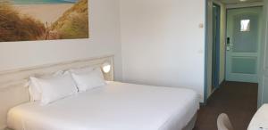 a bedroom with a white bed and a painting on the wall at Thalacap Île de Ré - Thalasso & Spa in Ars-en-Ré +37 photos