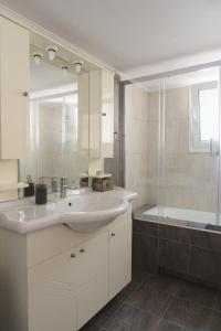 y baño blanco con lavabo y ducha. en Bright 2bd apt, garden view & parking - Glyfada, en Atenas