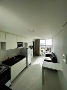 uma cozinha com armários brancos e um sofá em Aquarius Residence em Fortaleza