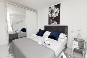 a white bedroom with a large bed with blue pillows at Katja Malo Misto in Zadar
