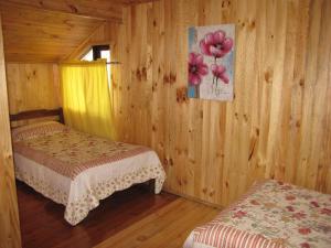 a bedroom with two beds in a wooden cabin at Hostal Austral in Ancud