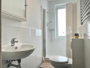 a white bathroom with a sink and a toilet at Design Apartment - Kingsize Bett - Küche - Zentral in Hannover