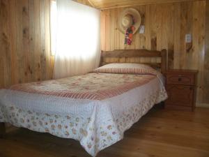 1 dormitorio con 1 cama con colcha blanca y ventana en Hostal Austral en Ancud