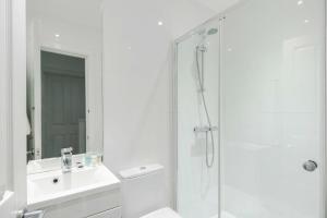 a white bathroom with a shower and a sink at Camden Town Duplex in London