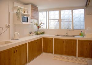 a kitchen with wooden cabinets and a sink at Home Story Hostel Chiang Mai in Chiang Mai