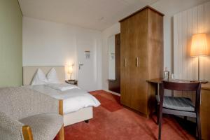 a bedroom with a bed and a desk and a chair at Pension Arosa - Self Check-In in Arosa