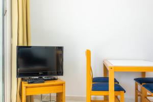a tv sitting next to a table with a blue chair at Apartament Massanet bb in Canyamel