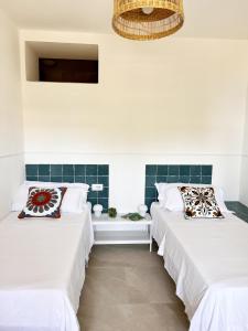 two beds in a room with white walls at Residenza Fontanelle-Beach Resort in Santa Maria di Castellabate