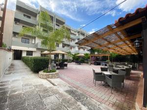 un patio con mesas y sillas frente a un edificio en Hotel Pavlos - Studios, en Tolo