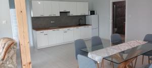 a kitchen with white cabinets and a glass table at Mazurskie Wzgórze BIS z basenem.3i4 in Rydzewo