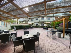 un patio esterno con tavoli, sedie e ombrelloni di Hotel Pavlos - Studios a Tolo