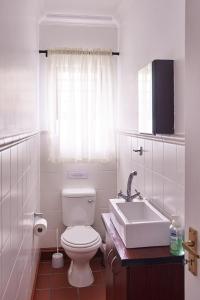 a white bathroom with a toilet and a sink at 2 The Mews - easy walk to town and the CVC in Clarens