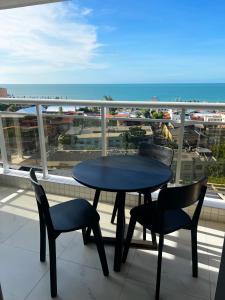 einen Tisch und Stühle auf einem Balkon mit Blick auf den Strand in der Unterkunft Aquarius Residence in Fortaleza