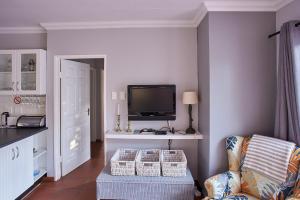 sala de estar con TV y silla en 2 The Mews - easy walk to town and the CVC en Clarens