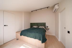 a bedroom with a bed with a green blanket at New flat with free underground parking and air conditioning in Rīga