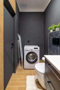 a bathroom with a washing machine and a toilet at New flat with free underground parking and air conditioning in Rīga