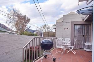 a grill on a patio with chairs and a house at 2 The Mews - easy walk to town and the CVC in Clarens