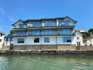 a large building on the water next to a river at 3 The Boatyard - Luxurious waterside 4 bed townhouse, lift, parking in Kingsbridge